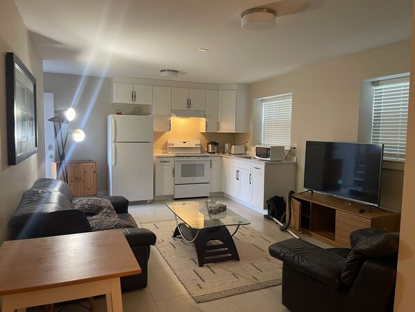 A compact living space with a kitchenette, a flat-screen TV, a sofa, and a coffee table.