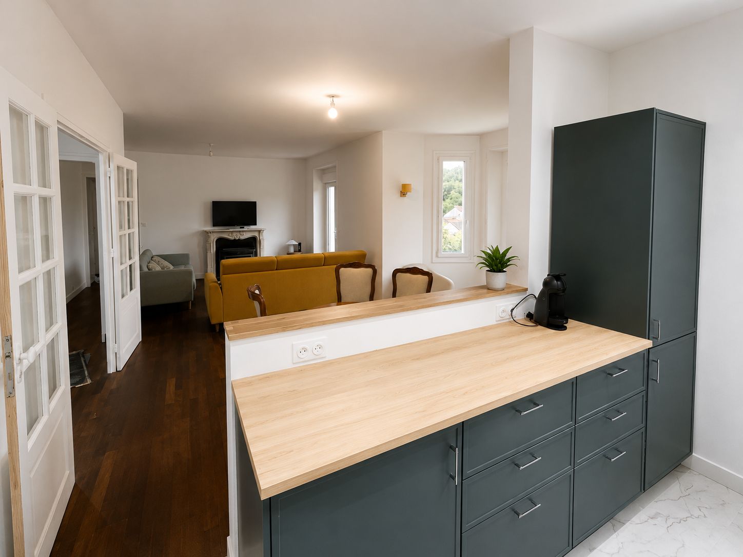 Una cocina moderna con encimera de madera, armarios empotrados y un refrigerador de color oscuro.