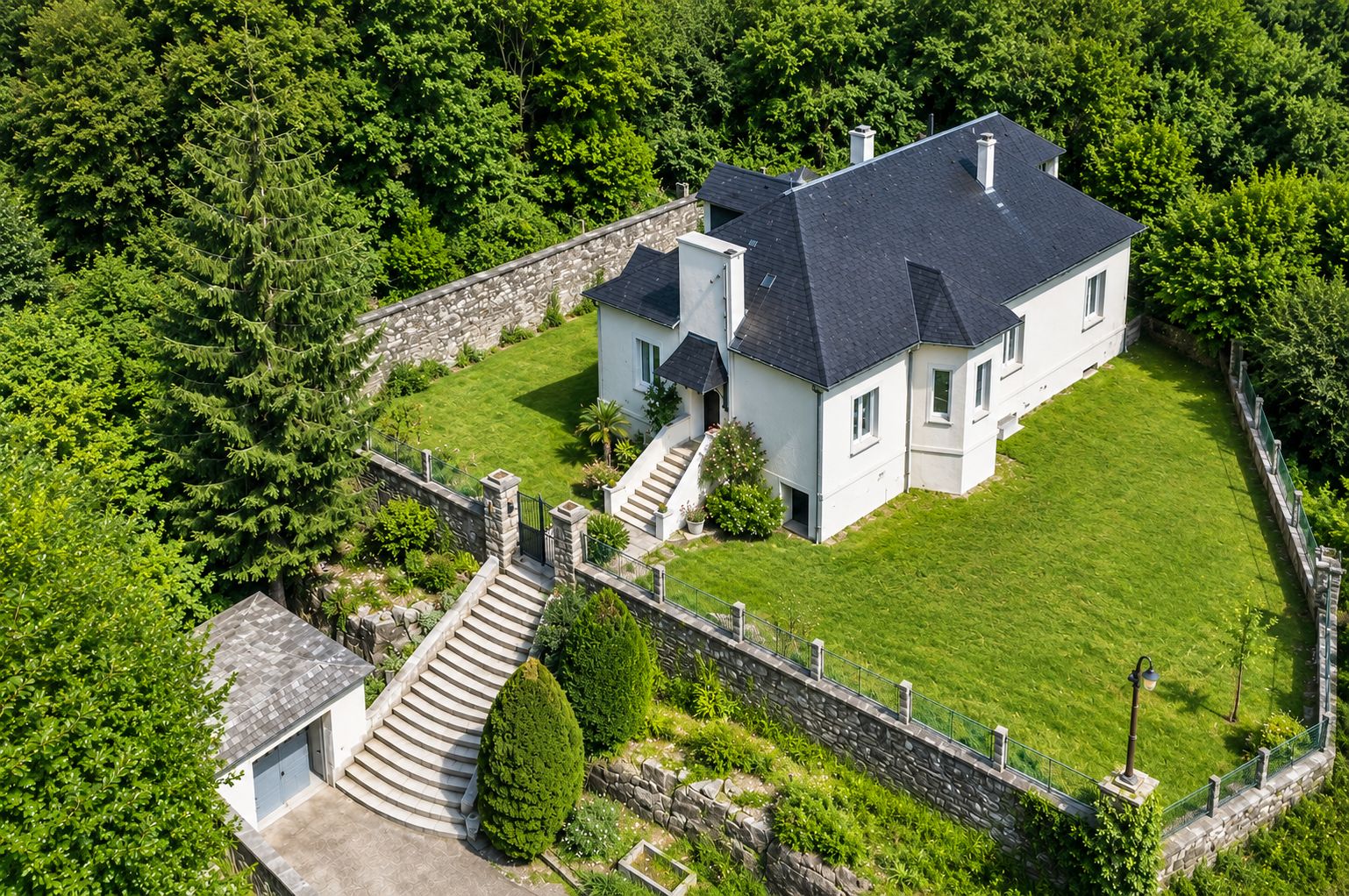 A large, two-story house with a stone wall and a well-maintained lawn.