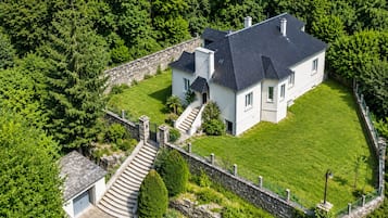 A large, two-story house with a stone wall and a well-maintained lawn.