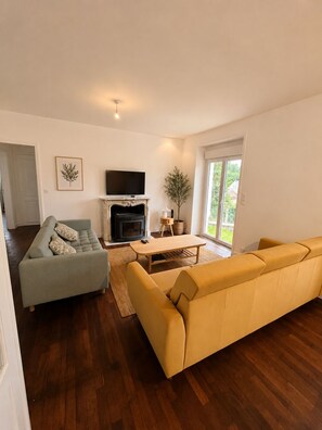 A modern living room with a fireplace, sofas, and a television. - Ti Ar Meliner – In the Heart of Brittany’s Natural Beauty (langonnet)