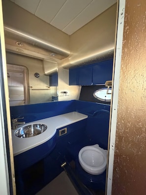 Ein kleines Badezimmer mit Waschbecken, Toilette und Spiegel.