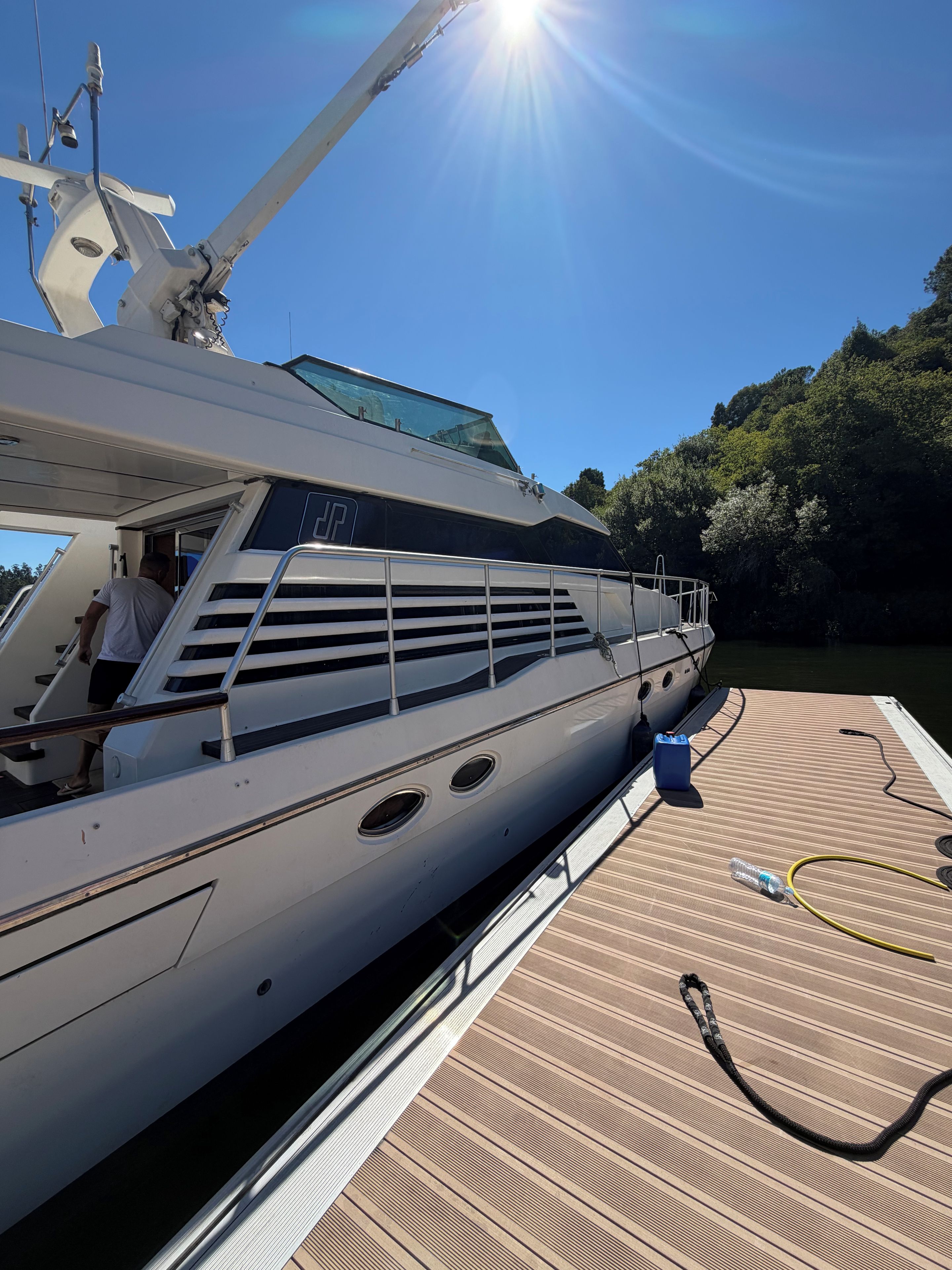 Eine Yacht mit Deck, eine Person auf dem Deck und ein klarer Himmel.