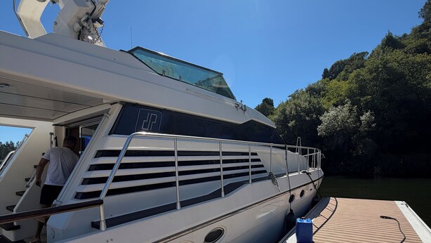Eine Yacht mit Deck, eine Person auf dem Deck und ein klarer Himmel.