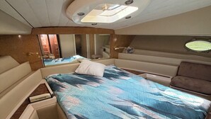 Ein kleines, gut beleuchtetes Schlafzimmer mit Bett, Nachttischen und einer Deckenleuchte.