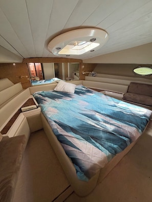 Ein kleines, gut beleuchtetes Schlafzimmer mit Bett, Nachttischen und einer Deckenleuchte.