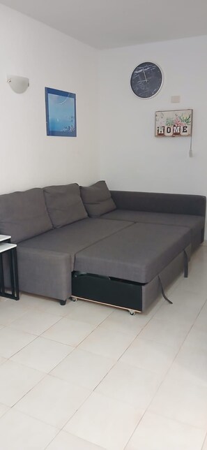 A modern living room with a sectional sofa, a small table, a wall clock, and a 'HOME' sign. - CABO PARAISO (Costa de Antigua)