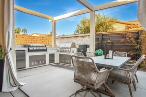 An outdoor patio with a grill, seating, and a view of the surrounding area. - La Quinta Oasis w/Pool, Hot Tub, Outdoor Kitchen, 4bedrooms/4baths (La Quinta)