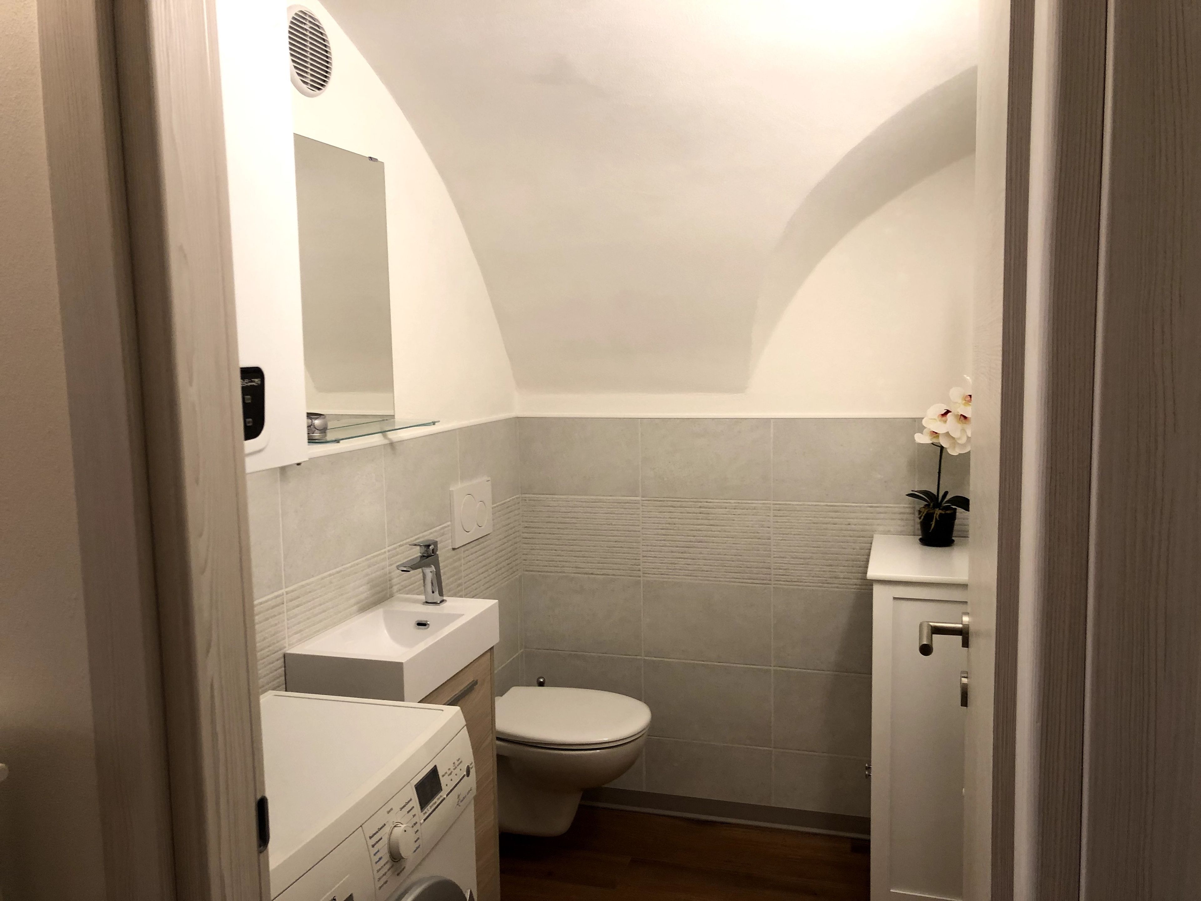 A compact bathroom with a toilet, sink, and a washing machine.