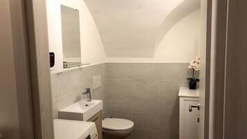 A compact bathroom with a toilet, sink, and a washing machine.