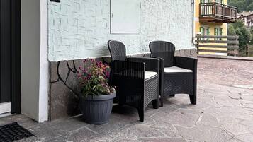 Ein Sitzbereich im Freien mit Korbmöbeln, einem Blumentopf und einer strukturierten Wand.
