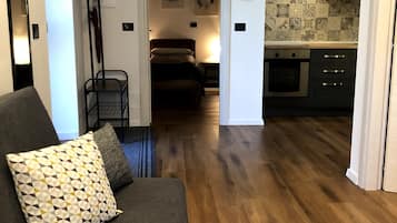 Ein modernes Wohnzimmer mit einer Couch, einem gemusterten Zierkissen und Holzboden.