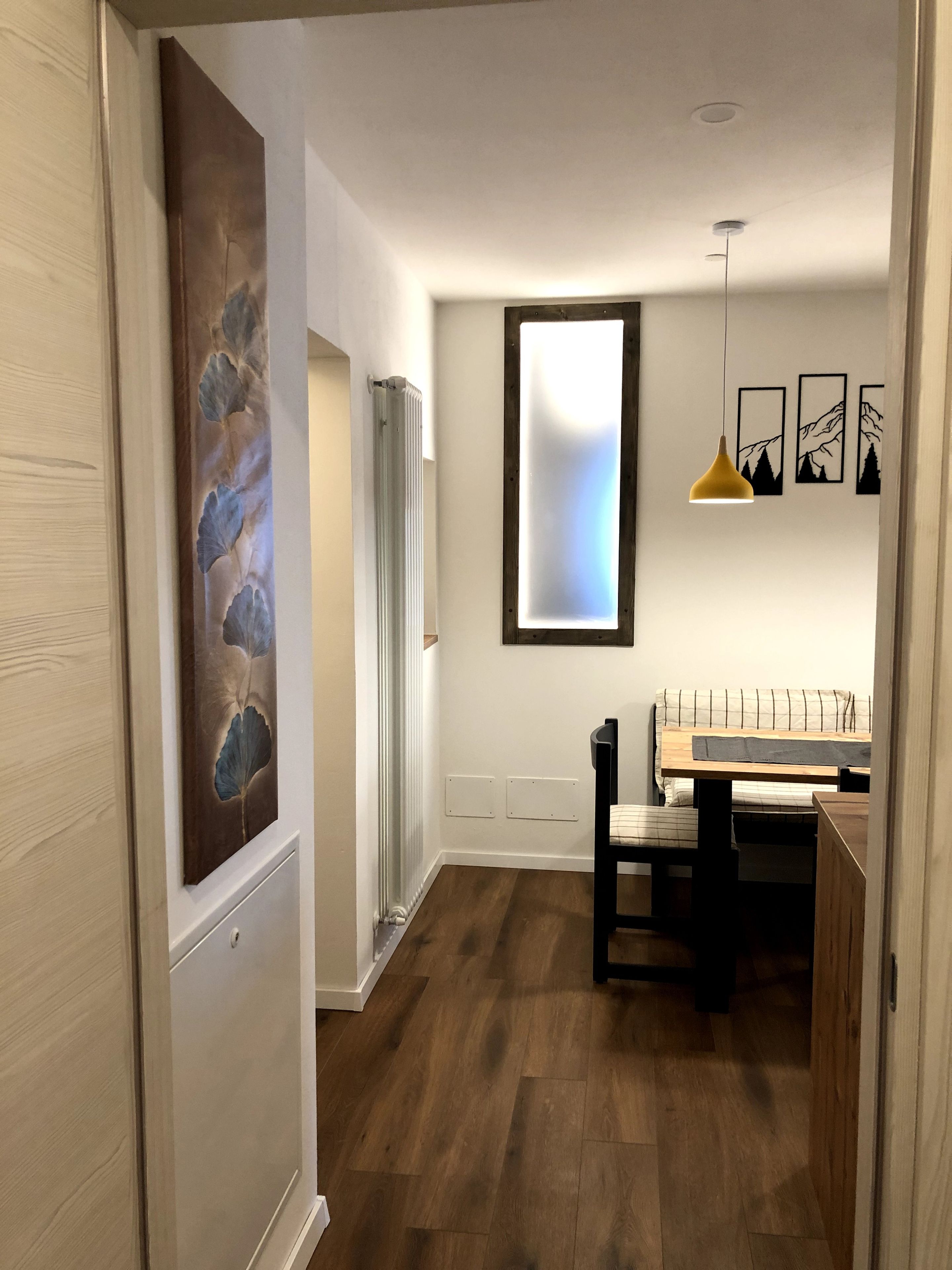 Eine moderne Küche mit Essbereich, Holzboden und einer Pendelleuchte.