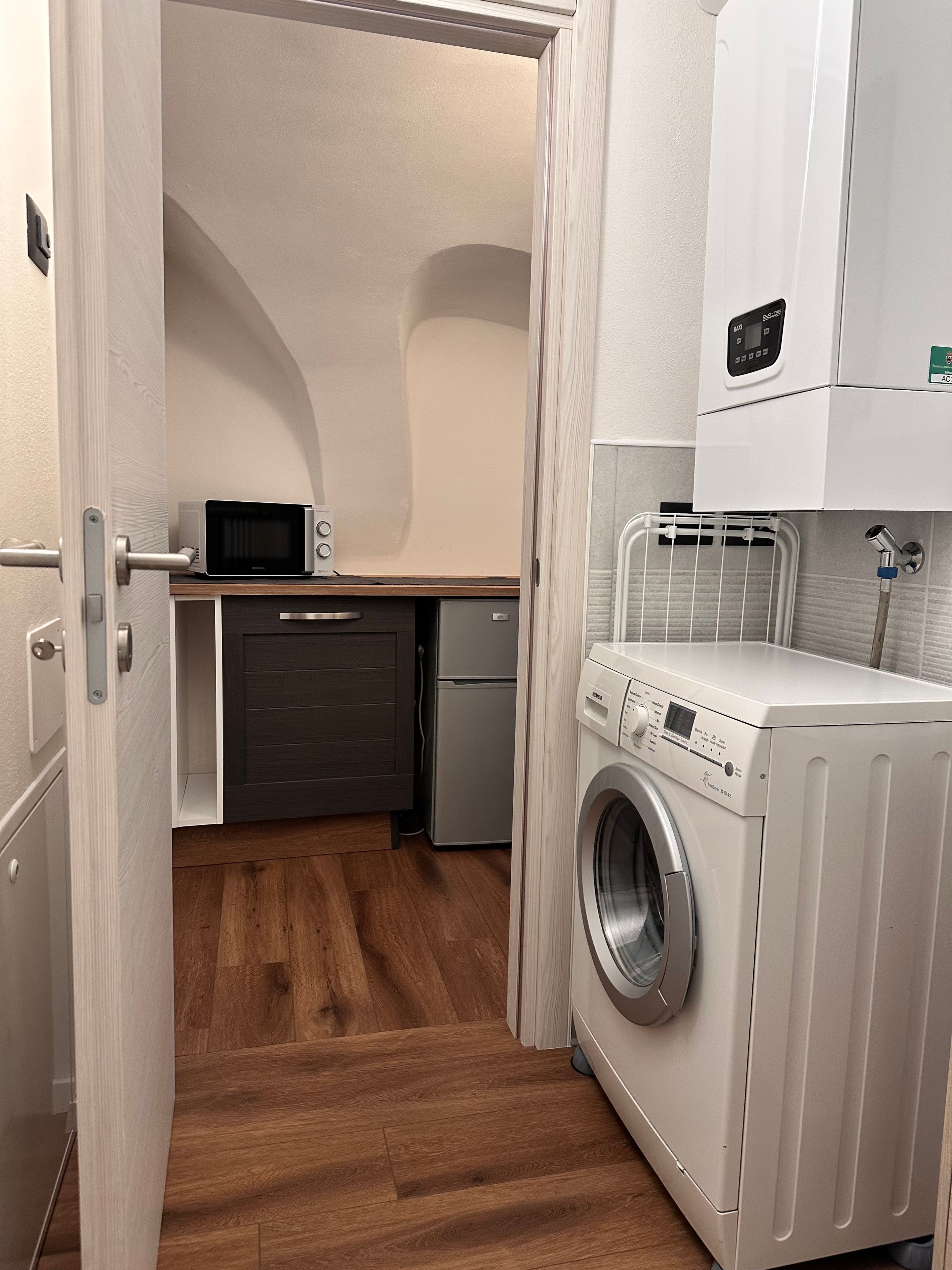 Eine kompakte Küche mit Mikrowelle, Kühlschrank und Waschmaschine.