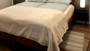A bedroom with a bed, two bedside lamps, a window with a wooden frame, and a patterned rug. - Vacation Home 'Ele Carano House' with Mountain View and Wi-Fi (Carano)