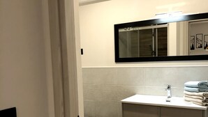 A modern bathroom with a white vanity, a mirror, and a towel stack. - Vacation Home 'Ele Carano House' with Mountain View and Wi-Fi (Carano)