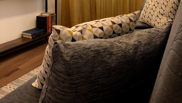 A living room with a sofa, a flat-screen TV mounted on the wall, a bookshelf with books, and a window with curtains. - Vacation Home 'Ele Carano House' with Mountain View and Wi-Fi (Carano)