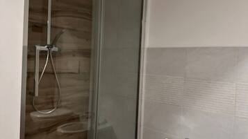 Une salle de bain moderne avec une douche à parois de verre, un lavabo blanc et un mur recouvert de carreaux.