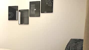 Un dormitorio con una cama, una silla y tres obras de arte enmarcadas en la pared.