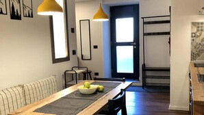 A dining area with a wooden table, black chairs, and a bench. There are two pendant lights, a window, and a door in the background. - Vacation Home 'Ele Carano House' with Mountain View and Wi-Fi (Carano)
