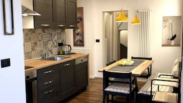 Una cocina moderna con armarios oscuros, encimera de madera y comedor con mesa y sillas.