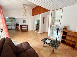 A living room with a sofa, a coffee table, a fan, and a wooden cabinet.