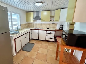 A compact kitchen with a refrigerator, sink, stove, and cabinets.