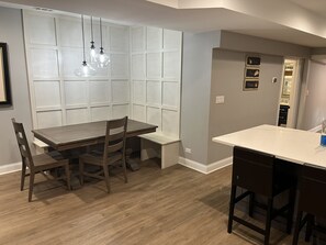 A modern kitchen with a wooden dining table, bar stools, pendant lighting, and a built-in pantry. - Little Italy 1BR Apartment just off Taylor Street (Chicago)