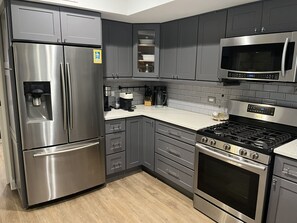 A modern kitchen with stainless steel appliances, grey cabinetry, and a tiled backsplash. - Little Italy 1BR Apartment just off Taylor Street (Chicago)