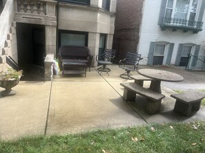 An outdoor patio area with a stone table and chairs, a small table, and a potted plant. - Little Italy 1BR Apartment just off Taylor Street (Chicago)