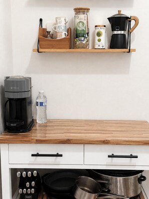 A kitchen with a coffee maker, a water bottle, and a pot on the counter.