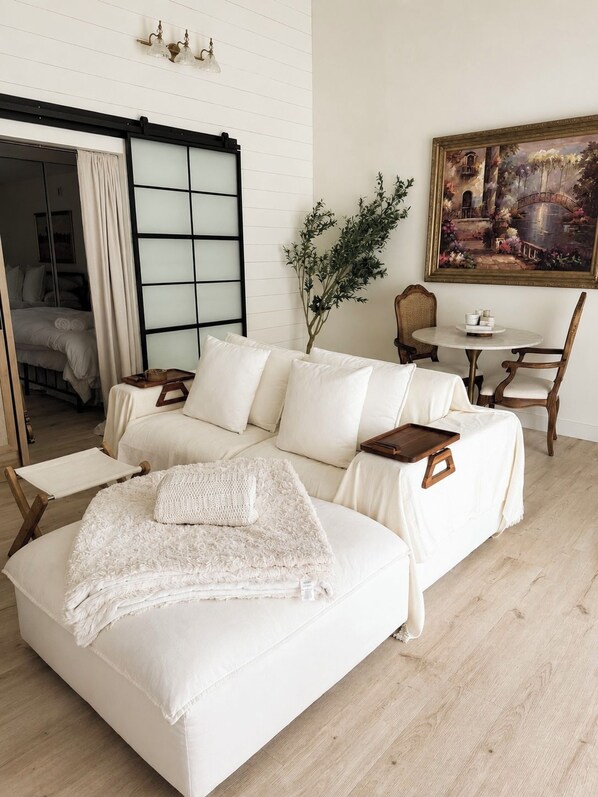 A modern living room with a sofa, a dining table, and a painting on the wall.