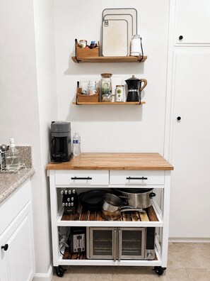 A kitchen with a wooden countertop, a coffee maker, a toaster, and a built-in oven.