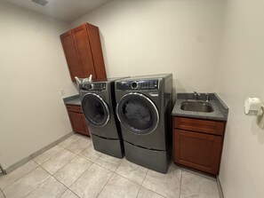 A laundry room with two front-loading washing machines, a sink, and wooden cabinets. - Large Modern Mountain Lodge in Forest near Lake Mary - Sleeps 12 - Pets OK (Flagstaff)