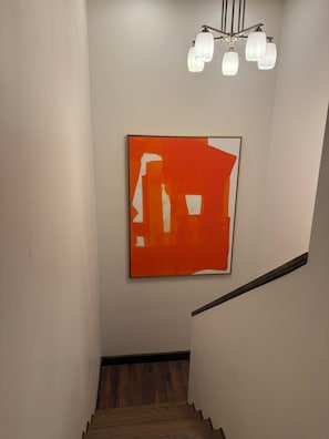 A staircase with wooden steps and a white wall. A modern light fixture hangs above. - Large Modern Mountain Lodge in Forest near Lake Mary - Sleeps 12 - Pets OK (Flagstaff)
