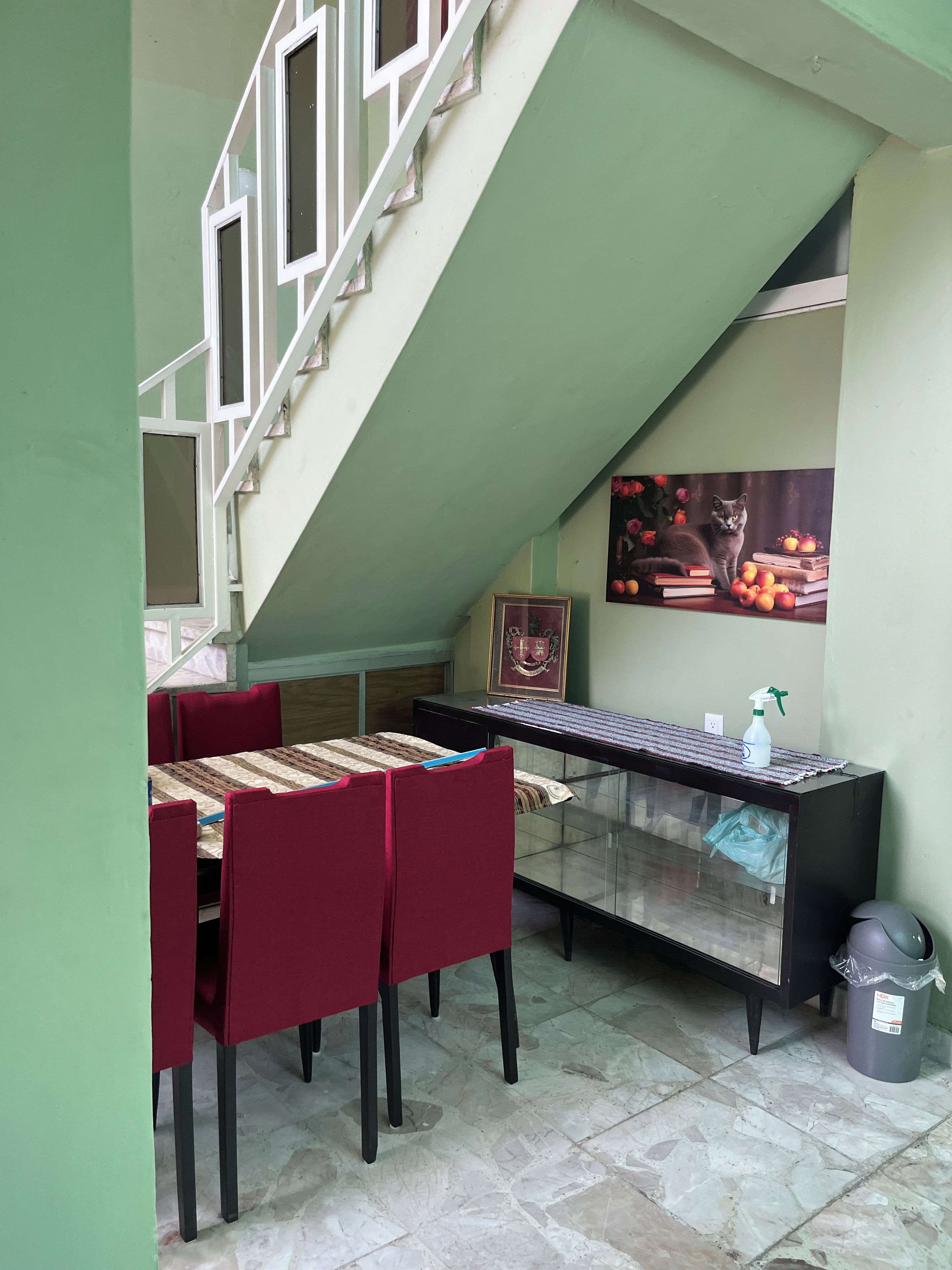 Un coin repas avec une table et des chaises, un escalier et un tableau accroché au mur.