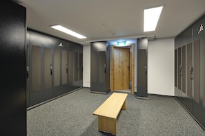 A locker room with multiple lockers, a wooden bench, and a door leading to another room. - Penthouse Suite With Panoramic Views (Gaschurn)