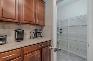 A kitchen with wooden cabinets, a countertop, and a coffee maker. - Spacious 5-bedroom house in peaceful Wimauma with AC (Wimauma)