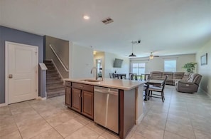 A spacious kitchen with a central island, a dining area with a sofa and chairs, and a staircase leading to another level. - Spacious 5-bedroom house in peaceful Wimauma with AC (Wimauma)