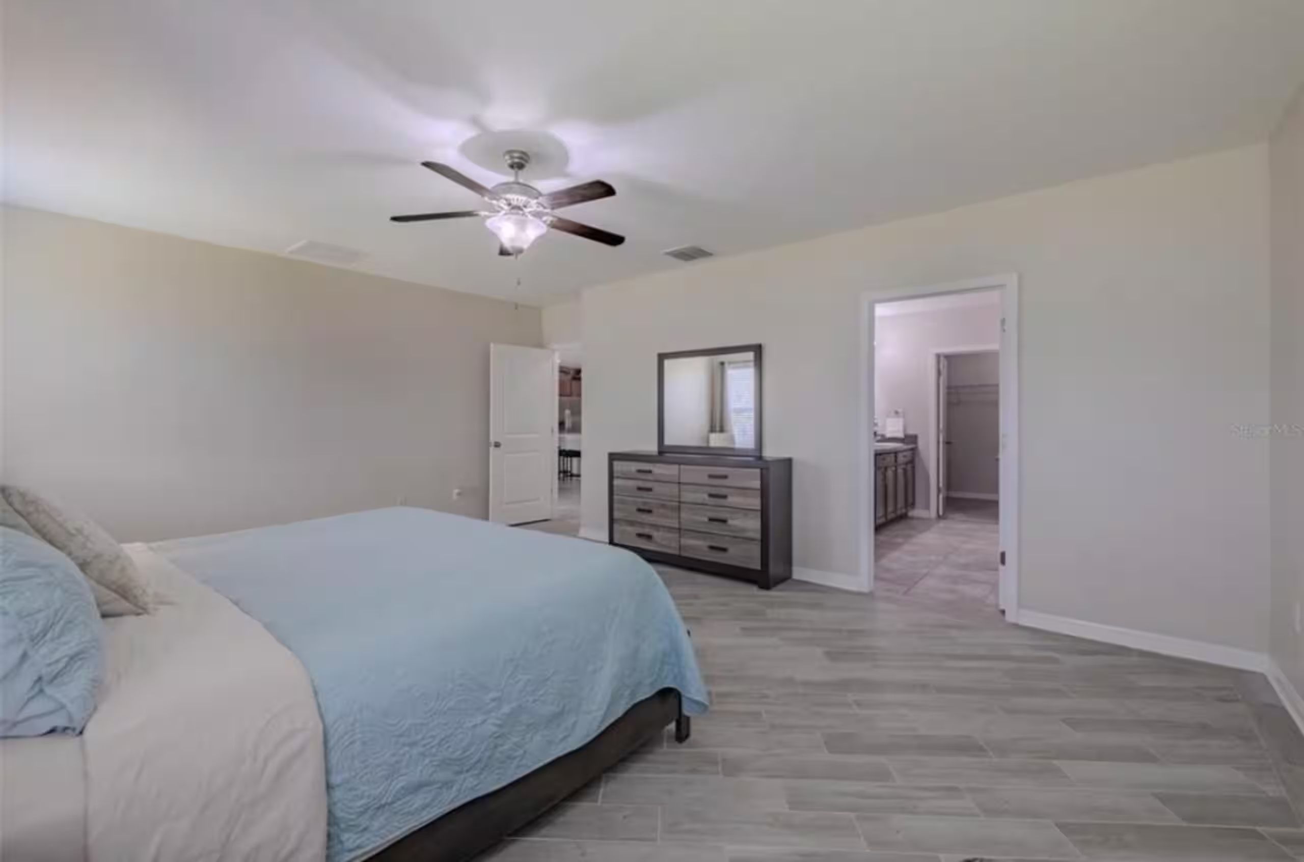 Un dormitorio con una cama, un aparador y un ventilador de techo.