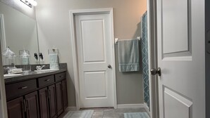 Un baño con una puerta blanca, un espejo, un lavabo y un perchero para toallas.