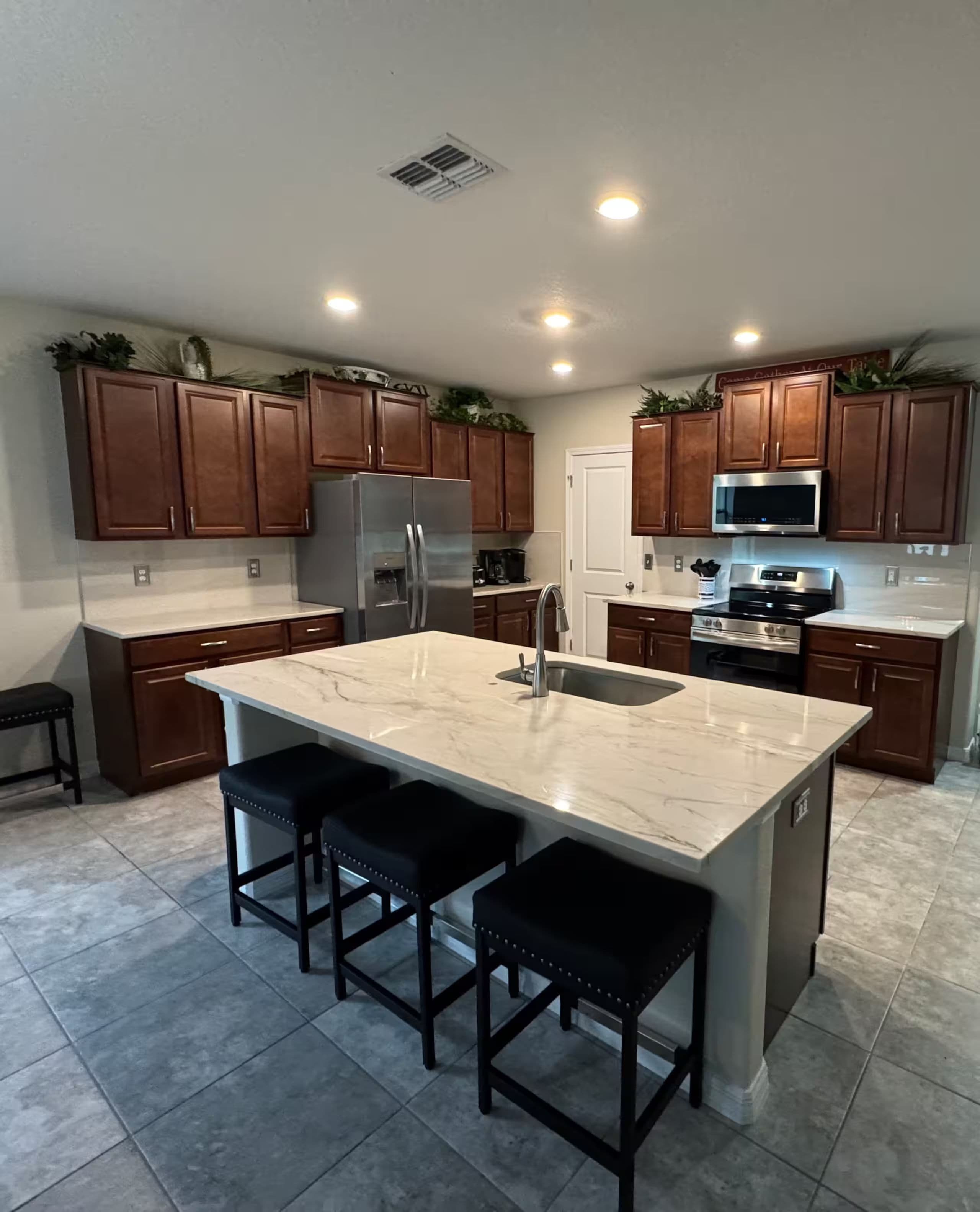 A modern kitchen with a central island, stainless steel appliances, and wooden cabinets.