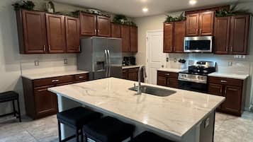 A modern kitchen with a central island, stainless steel appliances, and wooden cabinets.