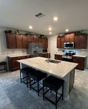A modern kitchen with a central island, stainless steel appliances, and wooden cabinets.