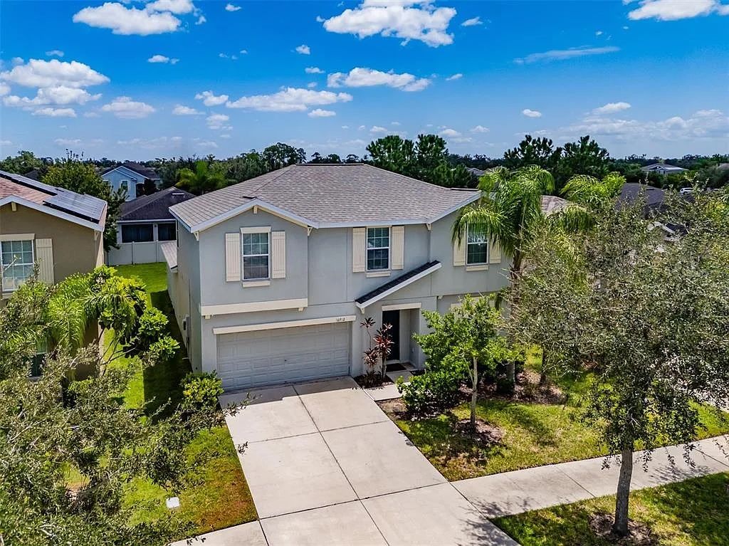 A residential house with a garage, a driveway, and a well-maintained lawn.