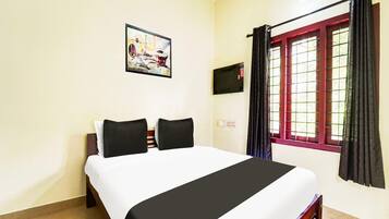 Habitación de hotel con cama, un cuadro en la pared, ventana con cortinas y televisor de pared.