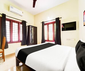Een hotelkamer met een bed, een garderobe, een televisie en een airconditioning.