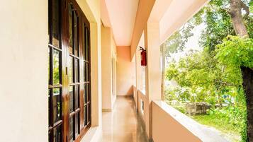 Un pasillo con un extintor fijado en la pared, que conduce a un ventanal con vistas a un jardín.