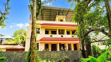 A multi-story building with a red roof, surrounded by lush greenery and trees.