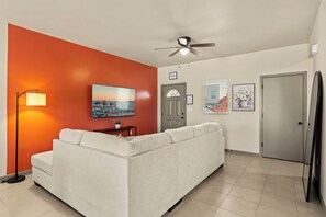 A living room with a white sofa, a ceiling fan, a floor lamp, and a cityscape painting on the wall. - 3BR 2.5BA Modern Farmhouse • King Bed • Smart TVs A (El Paso)